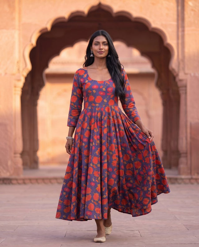 Woman in a purple and orange floral print flared anarkali dress at a sandstone arch