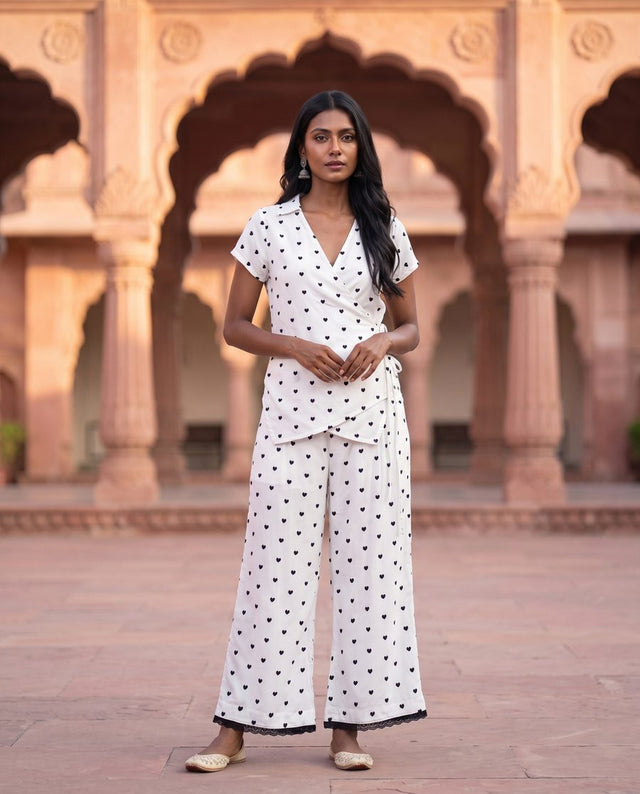 Front view of white wrap top with heart print and matching straight trousers